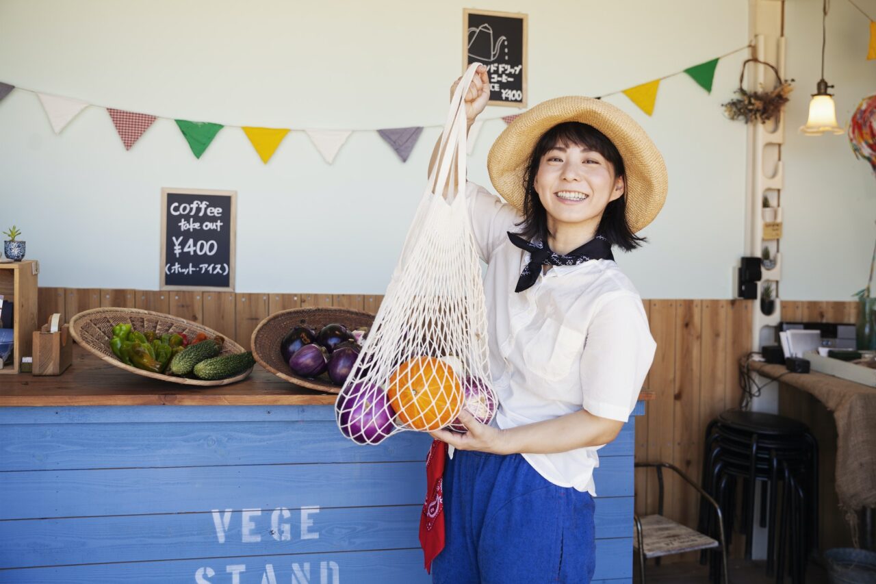 中国ビジネスモデルコンテスト 2023「龍の門」(Dragon Gate) 2 Japanese woman wearing hat working in a farm shop, smiling at camera.